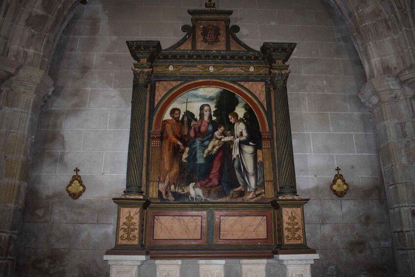 A religious painting with a central figure, flanked by others, in an ornate frame with a coat of arms. 5