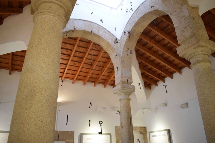 An interior with stone columns, wooden beams, and hanging keys. 4