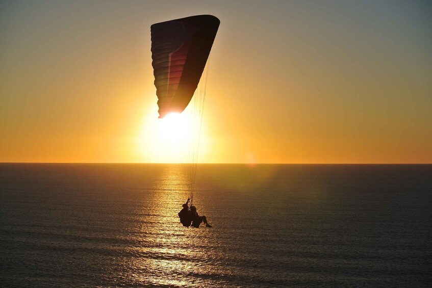 A person parasailing over the ocean at sunset. 4