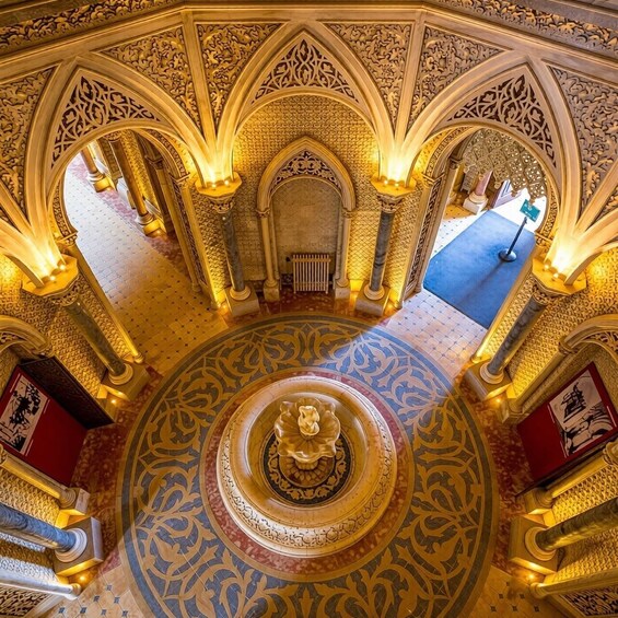 An ornate interior with intricate patterns, a central fountain, and a blue carpeted area. 3