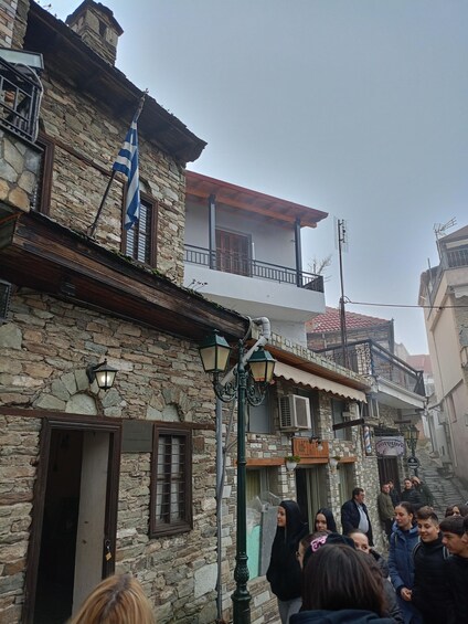 A stone building with a balcony, a flag, and a crowd of people. 5