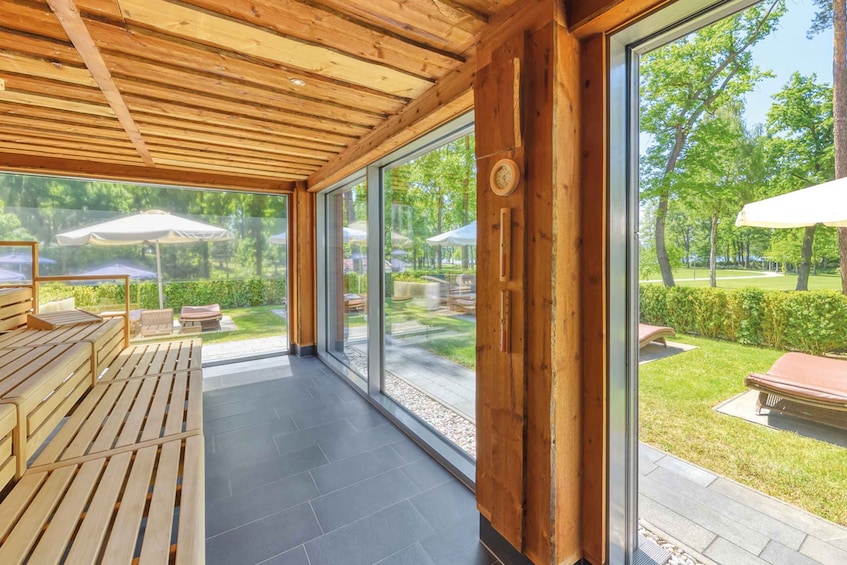 A wooden deck with outdoor seating and a glass wall overlooking a garden. 3