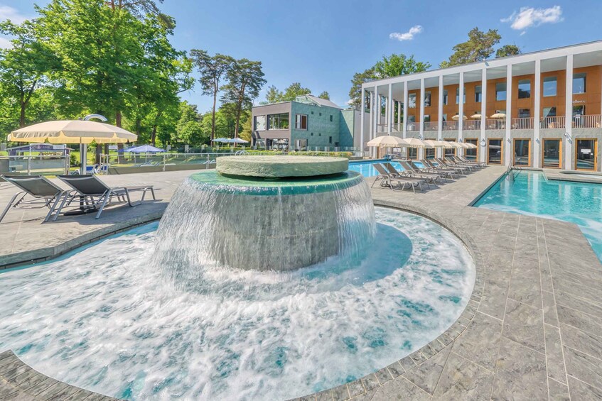 A swimming pool with a water feature, lounge chairs, and a building with a balcony. 1