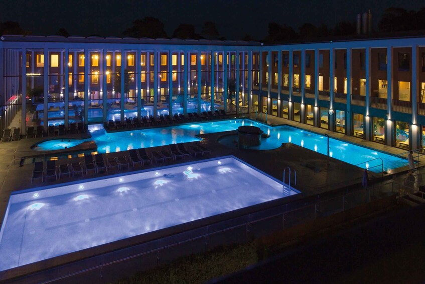 A swimming pool with lounge chairs and a heated area, surrounded by a building with illuminated windows. 4