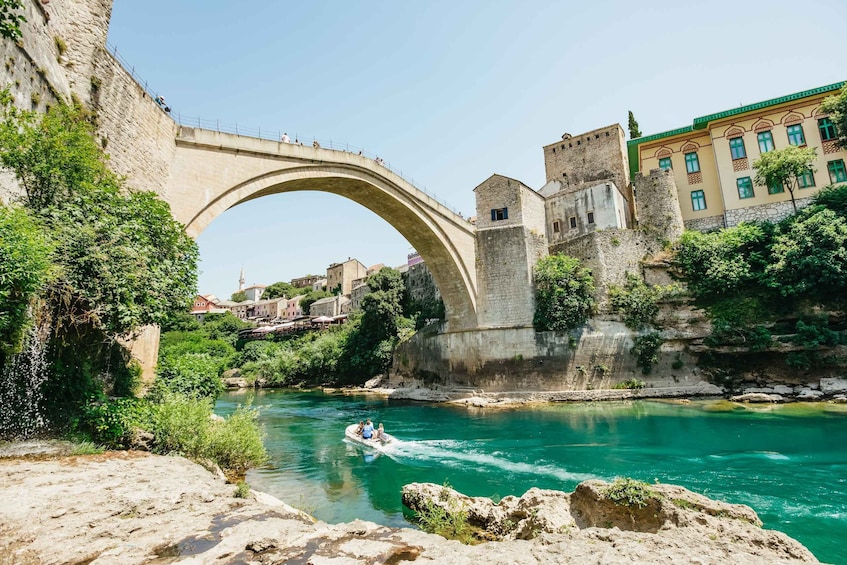 A stone bridge over a river, a castle, and a boat with people. 1