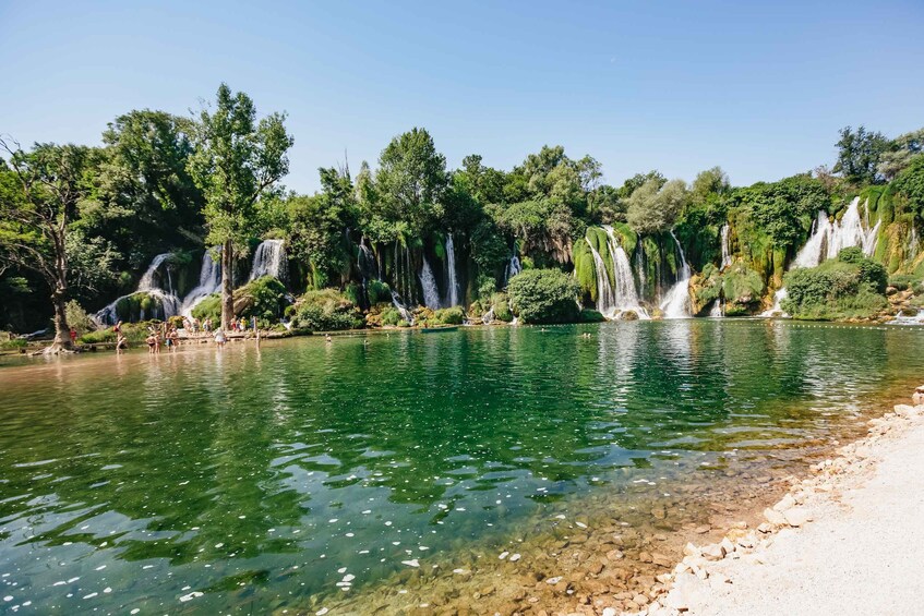 A clear lake with multiple waterfalls surrounded by lush greenery. 2