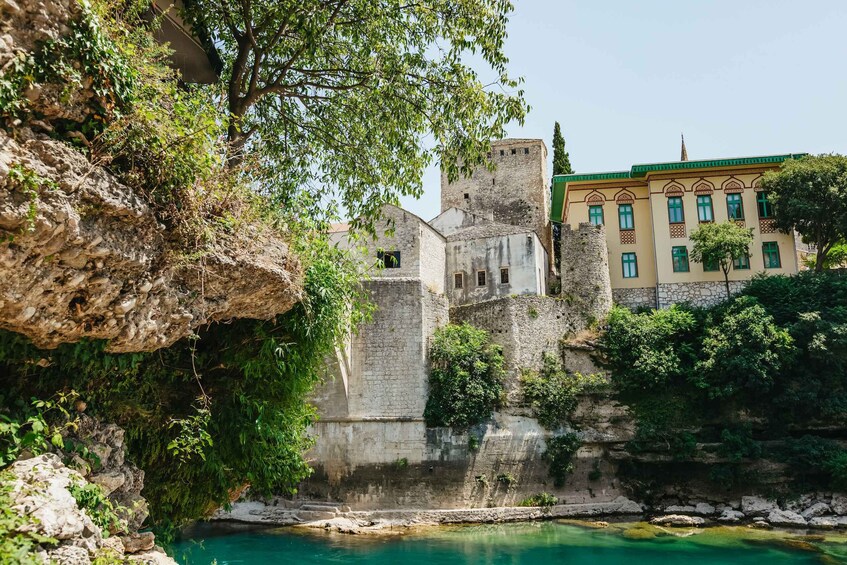 A historic stone building with a tower, a clear blue pool, and lush greenery. 3