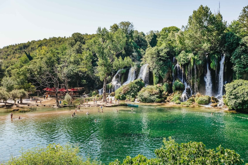 A serene waterfall cascading into a clear green lake surrounded by lush trees. 4