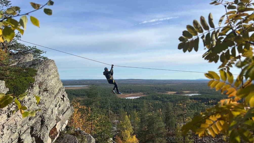 A person zip-lining across a rocky cliff with a forested valley below. 3