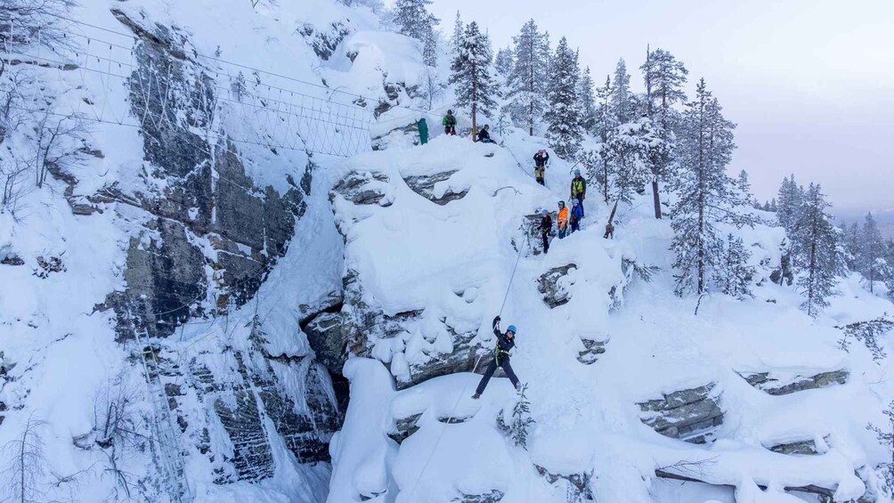 A snowy mountain with climbers ascending a steep slope. 1