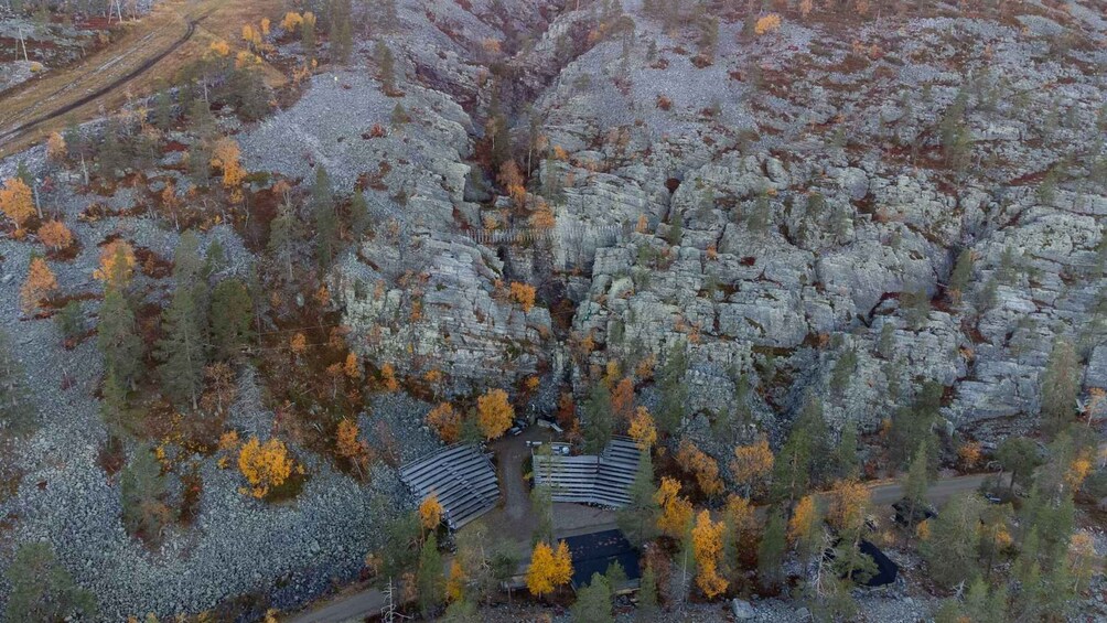 A rocky terrain with autumn-colored trees and a small building with a sloped roof. 5