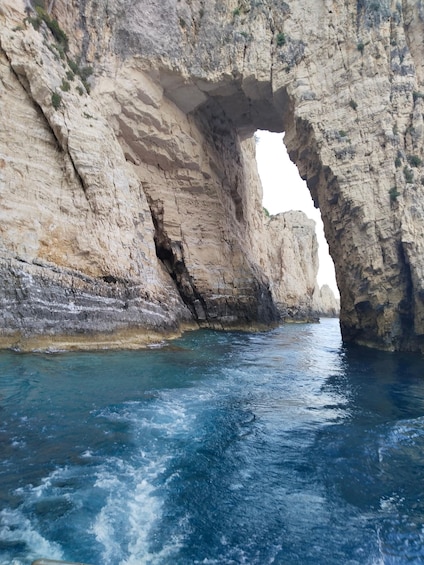 A coastal rock formation with a natural arch over clear blue water. 2