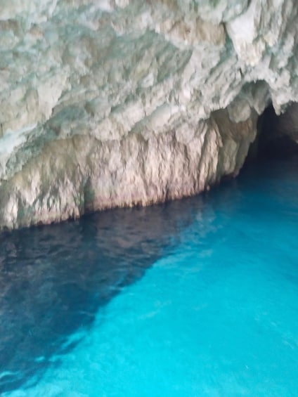 A cave with turquoise water and rocky walls. 5