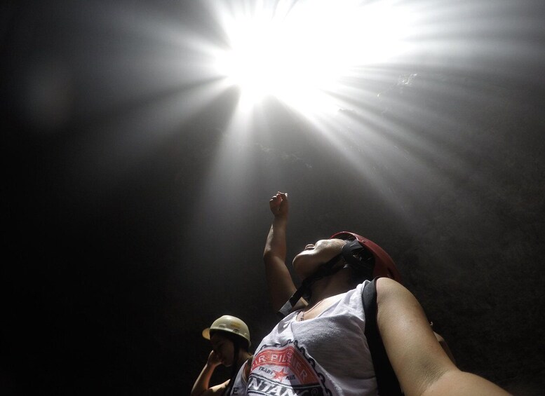 A person wearing a helmet and a tank top, with a bright light source above them. 5
