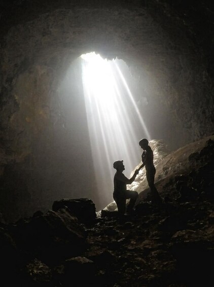 Two people in a cave with sunlight streaming through an opening. 1