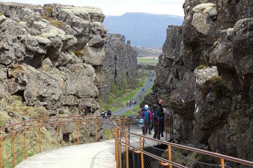 A rocky canyon with a paved walkway and a metal railing. 5
