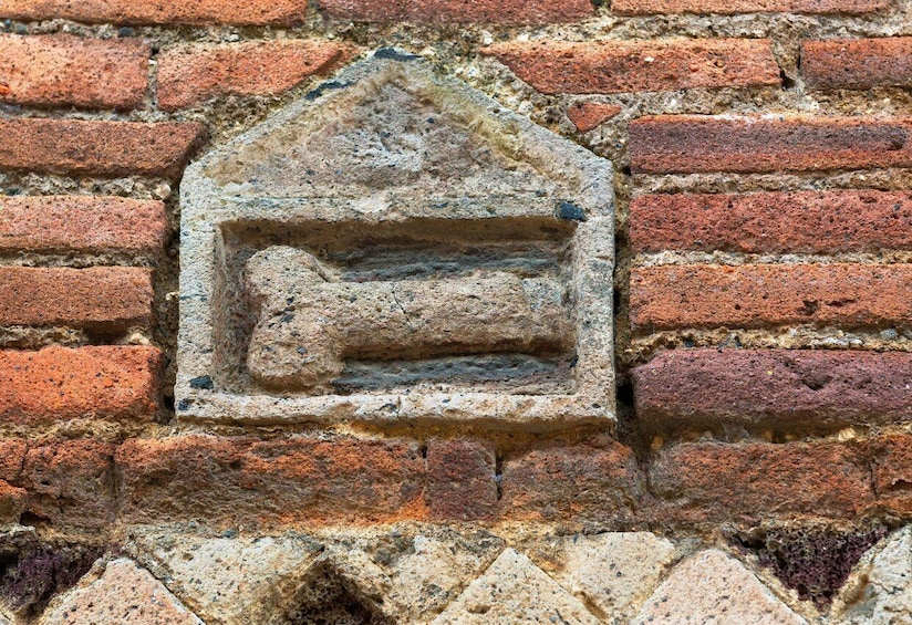 A brick wall with a stone plaque featuring a carved figure. 2