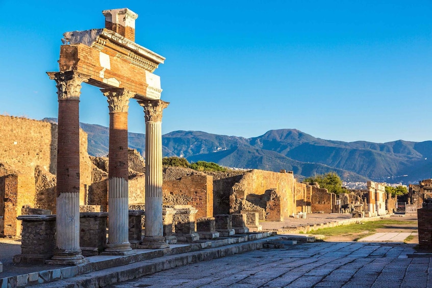 Ancient ruins with columns and a mountainous backdrop. 3