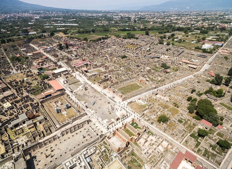 An aerial view of an ancient city with extensive ruins, including a large open square and surrounding structures. 5