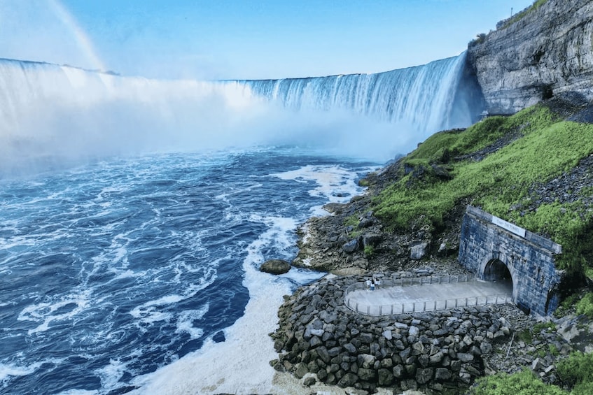 A large waterfall, a rocky shoreline, and a small bridge. 1