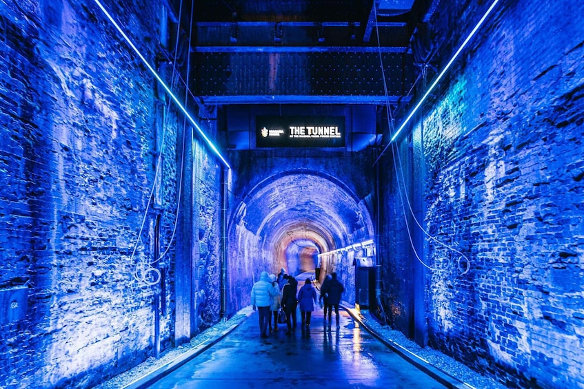 A tunnel with a sign reading 'THE TUNNEL' and people walking inside. 2