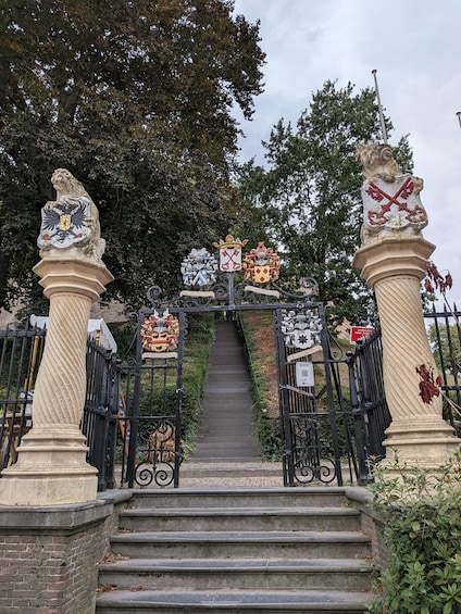 A staircase leading up to a gate with ornate coats of arms and a lion statue. 1