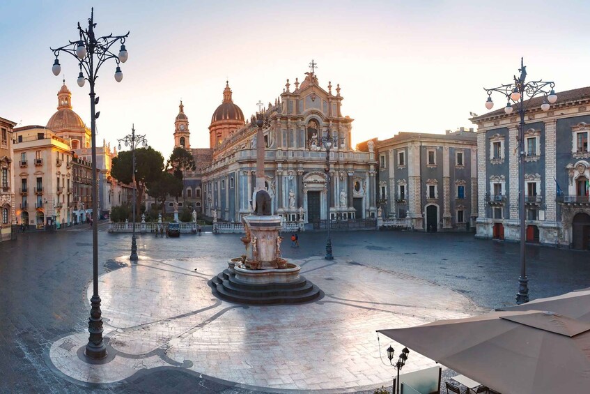 A plaza with a central fountain, surrounded by historic buildings with domes and intricate architecture. 1