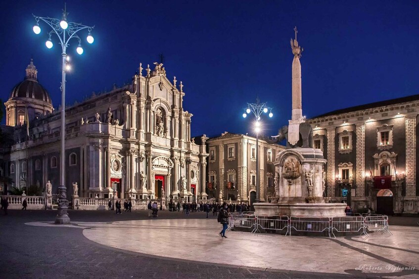 A historic square with a prominent church, a tall monument, and a fountain. 3