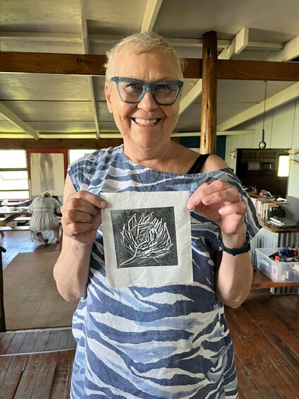 A person holding a square piece of paper with a white drawing. 4