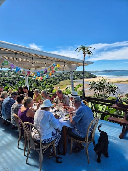 A group of people dining outdoors with a view of the beach and ocean. 2