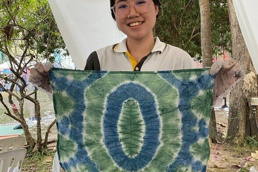 A person holding a tie-dye fabric with a central circular pattern. 5