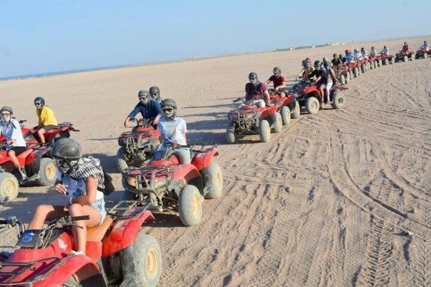 A line of people riding ATVs on a sandy beach. 5