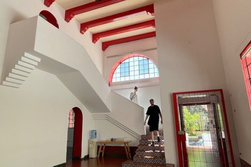 Un escalier agrémenté de touches de rouge, une grande fenêtre en arc de cercle et une porte à motifs géométriques. 2