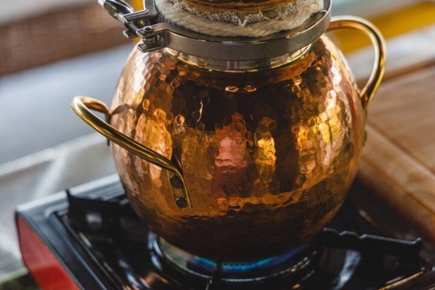 Une théière en cuivre sur une cuisinière. 1