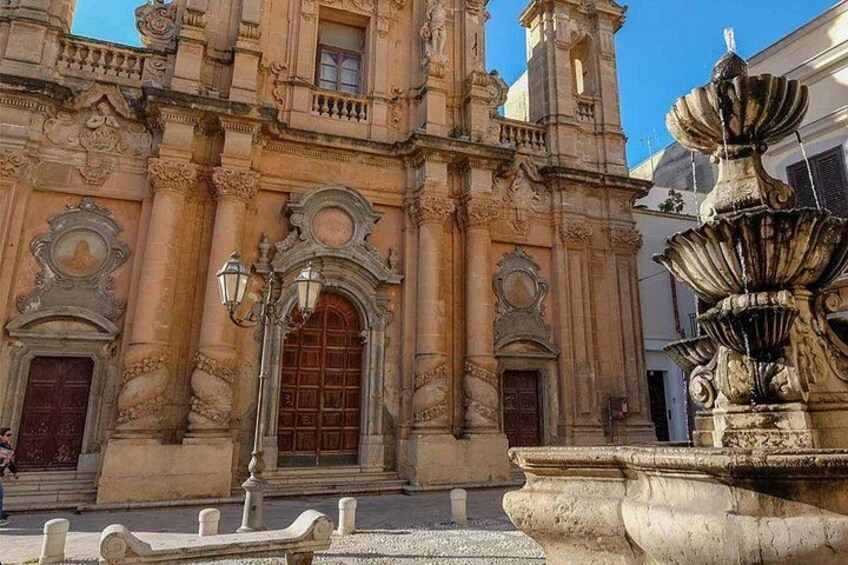 A historic building with ornate architecture, a prominent arched doorway, and a decorative fountain. 5