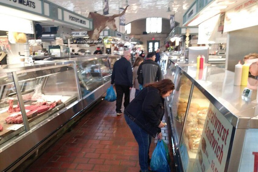 Een overdekte markt met glazen vitrines vol vlees, een slagersbalie en een bord met de tekst 'Pork Chops'. 2