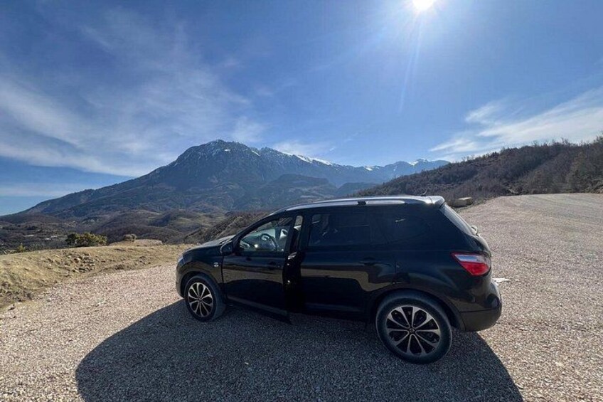 Un SUV nero parcheggiato su una strada sterrata, con un paesaggio montuoso sullo sfondo. 2