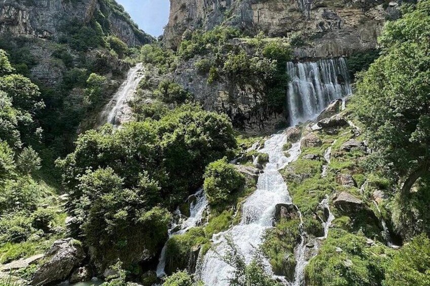 Una cascata che si getta da una parete rocciosa, circondata da una vegetazione lussureggiante. 1