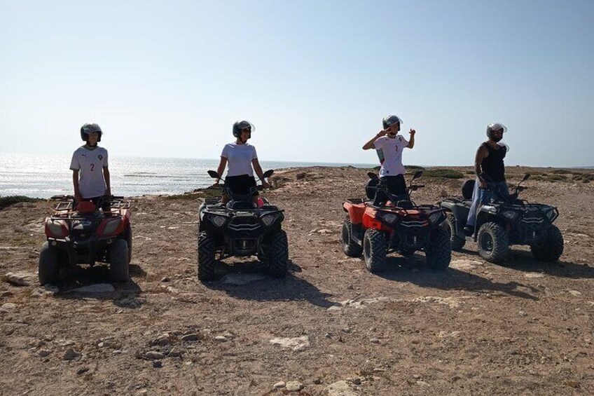 Tres personas en cuatrimotos sobre una playa arenosa, con el océano al fondo. 5