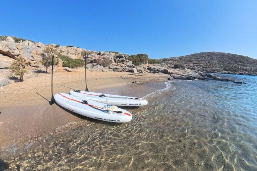 Zwei weiße Stand-Up-Paddles mit roten Akzenten an einem felsigen Strand mit klarem Wasser. 2