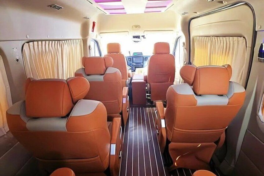 A vehicle interior with orange seats, a control panel, and curtains. 1