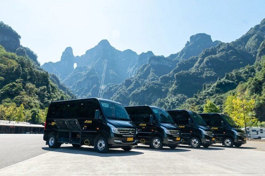 A row of black vehicles parked on a concrete surface with a mountainous landscape in the background. 3