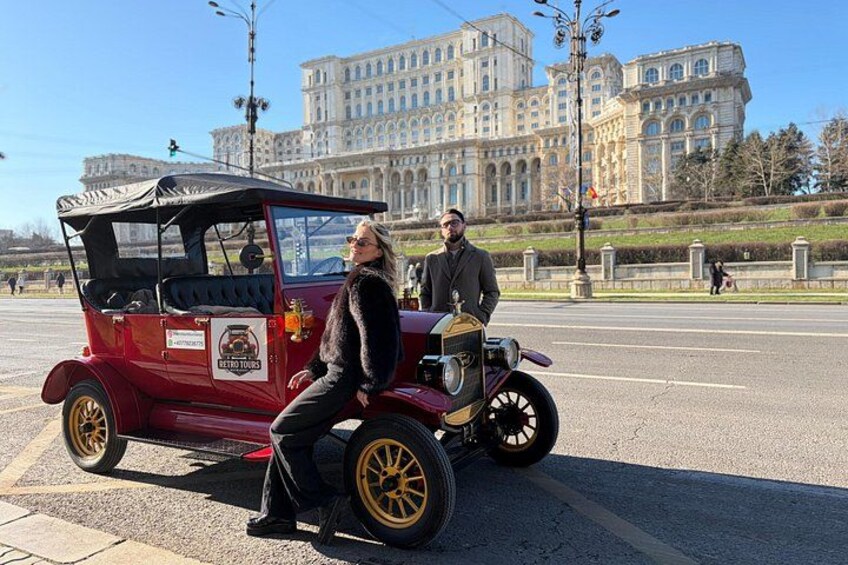 Un coche antiguo con un conductor y un pasajero en una intersección. 4