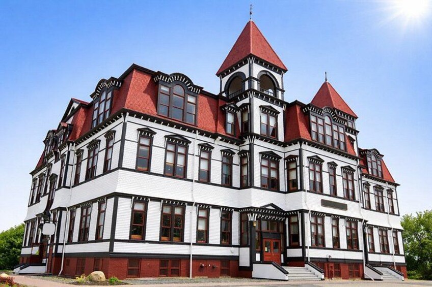 A large, historic building with a red roof, multiple towers, and a prominent entrance. 3