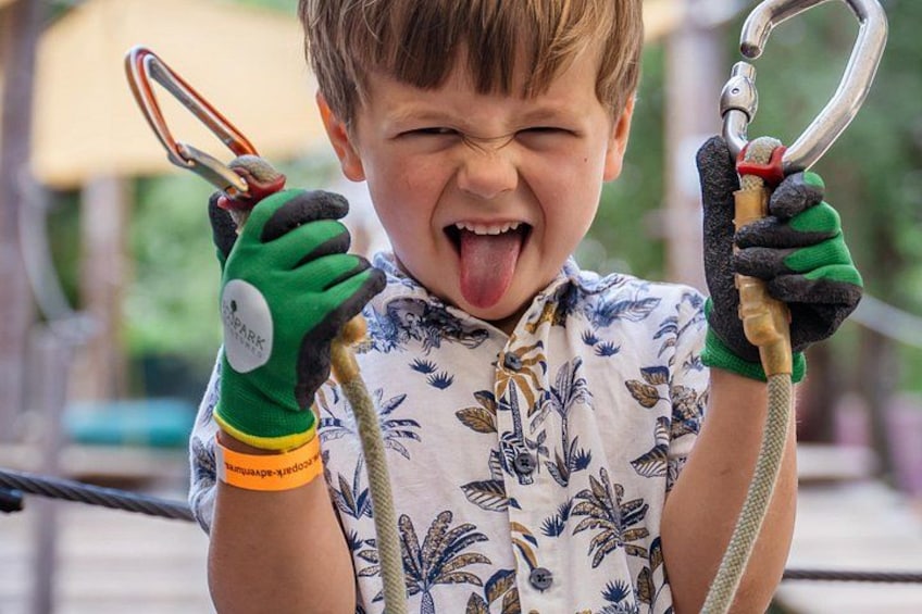 Un bambino che tiene una corda con un moschettone, indossa guanti e una camicia fantasia. 3
