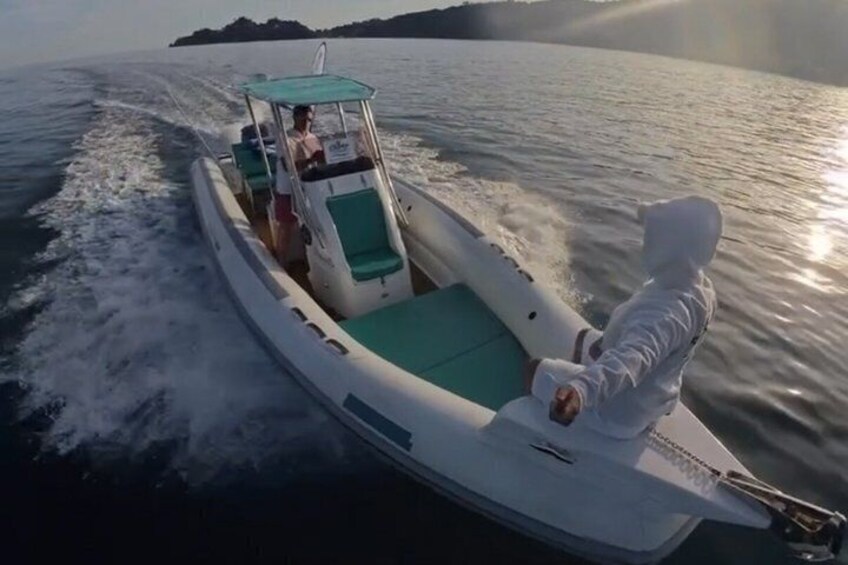 A boat with a person in a white hood, another person in a red shirt, and a third person in a white shirt on the water. 5