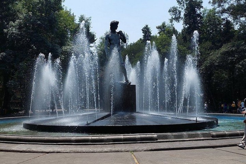 A fountain with water jets, a statue, and a circular pool. 1