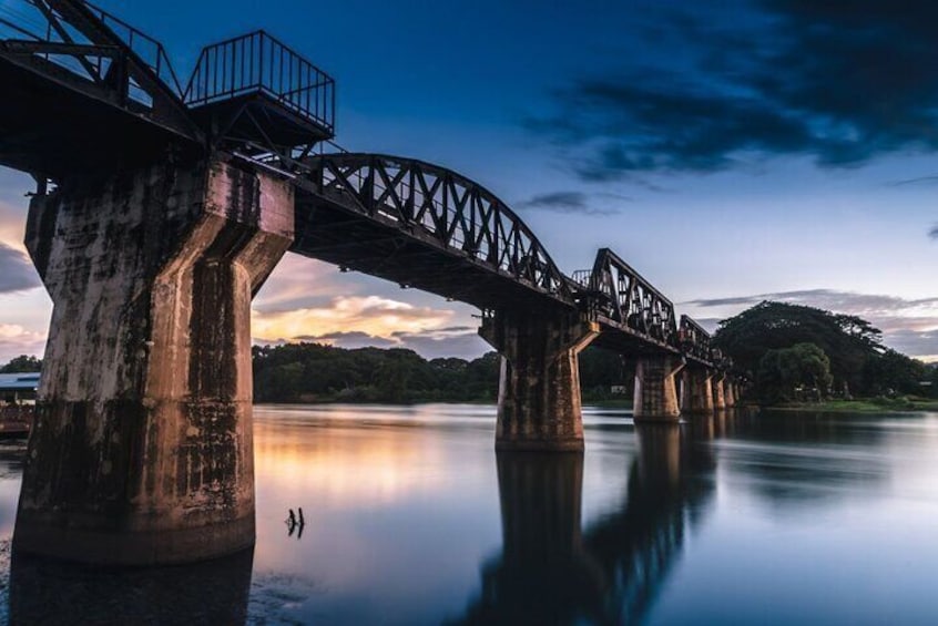 Een brug over rustig water, met een zonsondergang op de achtergrond. 1