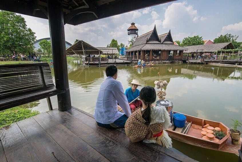 Een houten boot met passagiers, een rustige rivier en traditionele gebouwen op de achtergrond. 2