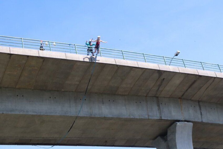 A concrete bridge with a metal railing and a person jumping off the edge. 5